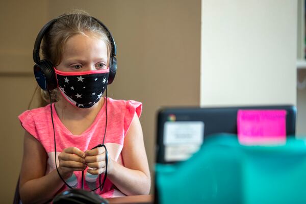 08/05/2020 - Marietta, Georgia - Ruby Waldron fidgets with her headphone cord while participating in virtual learning on a laptop at the Emily Lembeck Learning Center in Marietta, Wednesday, August 5, 2020. The learning center is part of the Marietta City Schools district. The Marietta City School System is offering childcare for staff while the district is operating on a virtual-only option. Each class will be staffed by MCS staff members, and no more than five children will be in each class to allow for social distancing. (ALYSSA POINTER / ALYSSA.POINTER@AJC.COM)