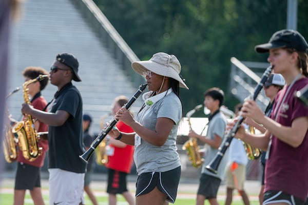 Some members of the North Gwinnett High School band take to neck fans and wide-brim hats to beat the heat during practice Wednesday, July 26, 2023.  (Jamie Spaar for The Atlanta Journal-Constitution)