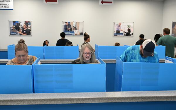 Gwinnett County voters, including Carol Humphries (center), complete ballots during early voting in Lawrenceville.