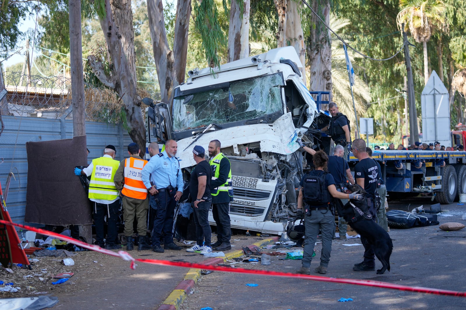 Israeli police and rescue services inspect the body of a truck driver that rammed into a bus stop near the headquarters of Israel's Mossad spy agency, wounding dozens of people, according to Israel's Magen David Adom rescue service in Tel Aviv, Israel, Sunday, Oct. 27, 2024. (AP Photo/Ohad Zwigenberg)