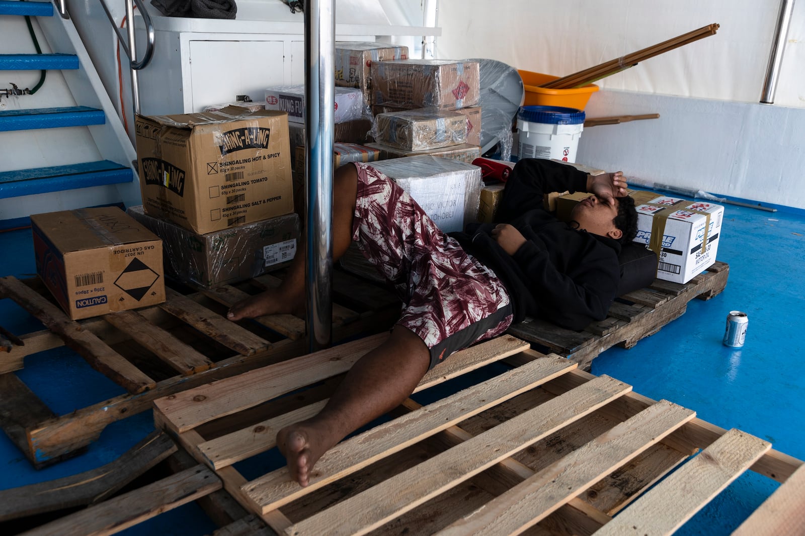 Maxson Blesson sleeps on a wooden pallets on the top deck of the Ryoma, a boat that brings goods through the Pacific Ocean to Helen Island, Palau, on July 15, 2024. (AP Photo/Yannick Peterhans)