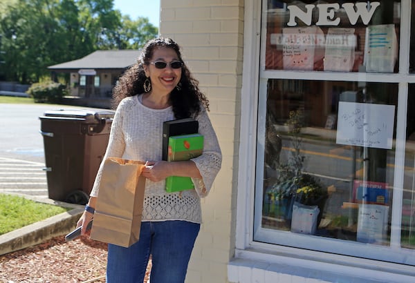 Susan Smelser, current owner of The Book Worm, waits for a customer to pick up a book purchase at The Book Worm on Friday, April 3, 2020, in Powder Springs, Georgia. The store is closed to customers due to social distancing concerns; however, books can can be purchased over the phone and picked up or shipped from the store. (Christina Matacotta, for The Atlanta Journal-Constitution)