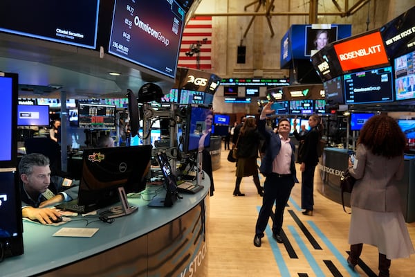 People take pictures while others work on the floor at the New York Stock Exchange in New York, Monday, Feb. 24, 2025. (AP Photo/Seth Wenig)