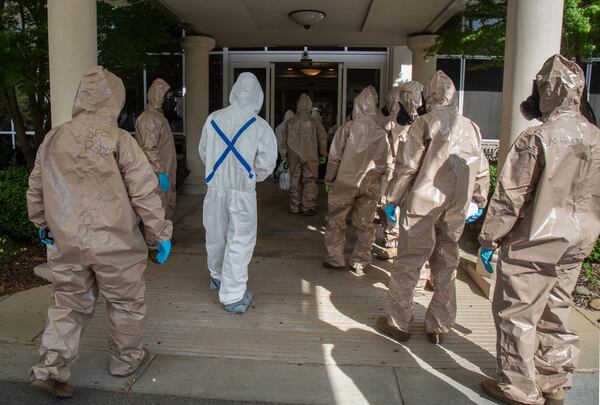 Members of the 265th Infectious Control GA Army National Guard enter a senior living facility in Buckhead Friday to clean the building. STEVE SCHAEFER / SPECIAL TO THE AJC