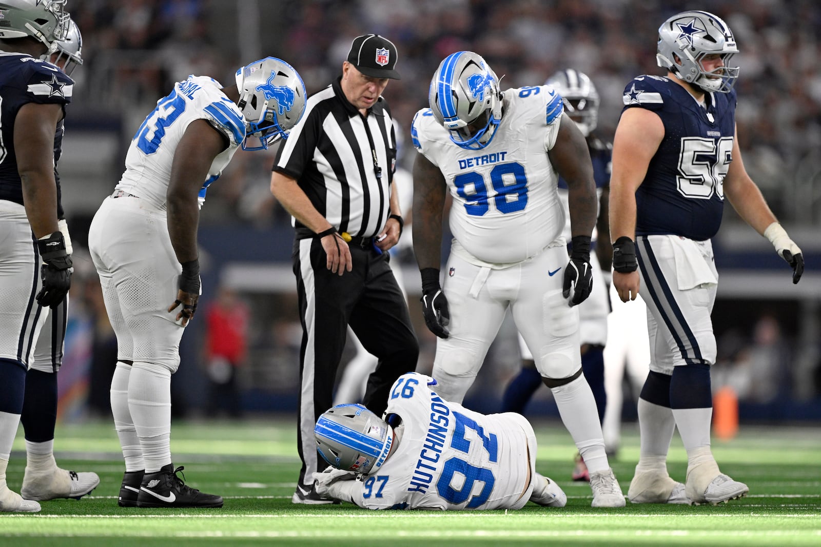 Detroit Lions' Aidan Hutchinson (97) is checked on by DJ Reader (98) and others after suffering an unknown injury in the second half of an NFL football game against the Dallas Cowboys in Arlington, Texas, Sunday, Oct. 13, 2024. (AP Photo/Jerome Miron)