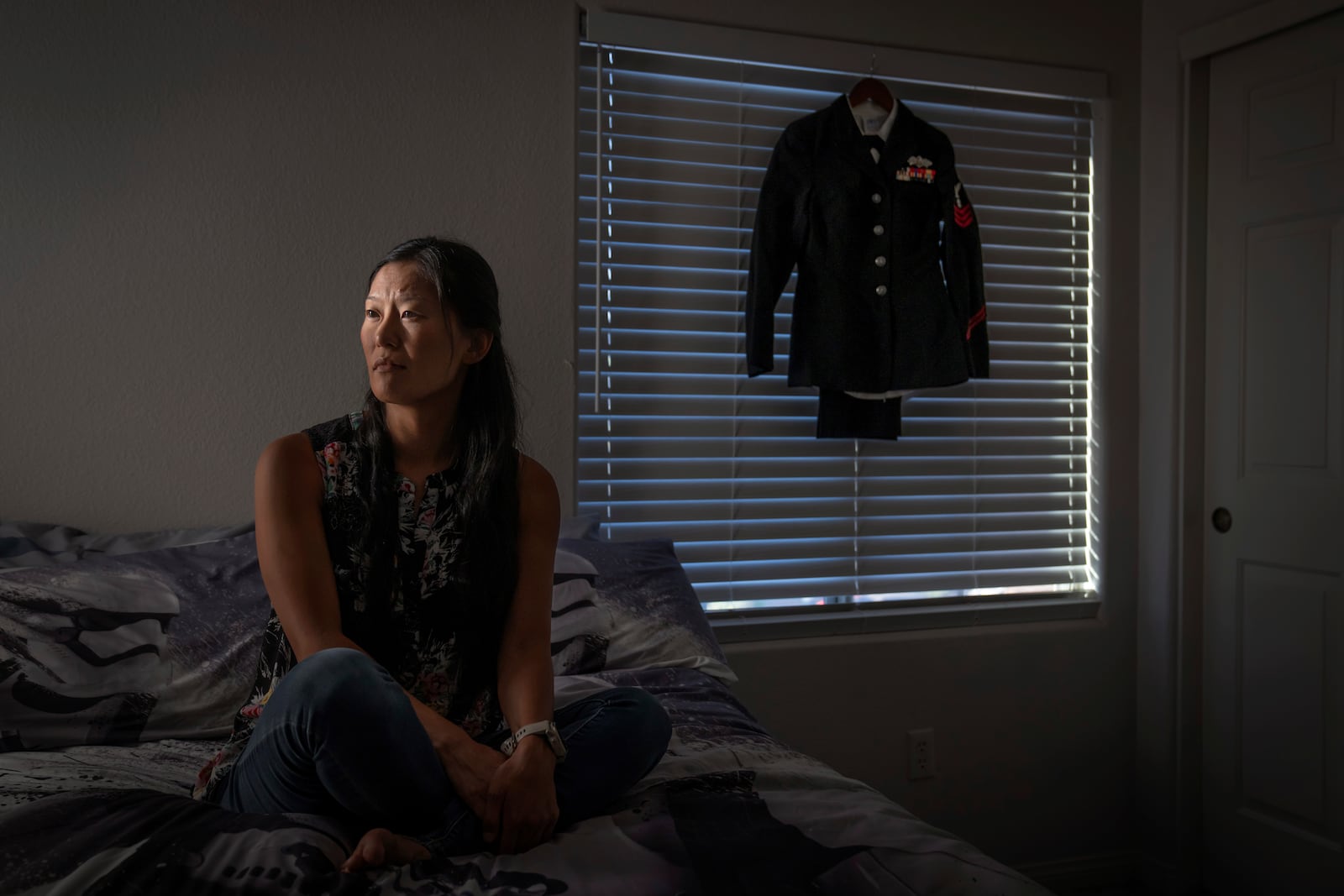 Leah Elmquist, sits for a portrait as her Navy uniform hangs in her home, Wednesday, June 26, 2024, in Las Vegas. Elmquist was among thousands of adoptees left without citizenship by loopholes in American law. She excelled in the military, but wasn't eligible for certain security clearances. She left after a decade, then laid low, fearing deportation. (AP Photo/David Goldman)