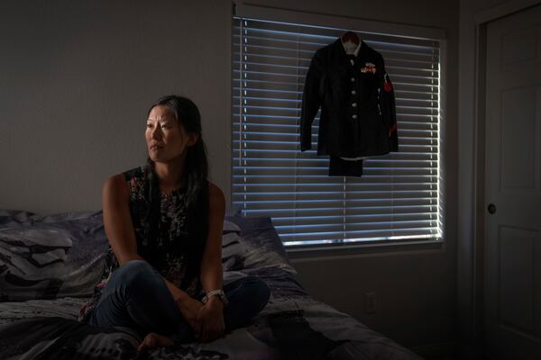 Leah Elmquist, sits for a portrait as her Navy uniform hangs in her home, Wednesday, June 26, 2024, in Las Vegas. Elmquist was among thousands of adoptees left without citizenship by loopholes in American law. She excelled in the military, but wasn't eligible for certain security clearances. She left after a decade, then laid low, fearing deportation. (AP Photo/David Goldman)