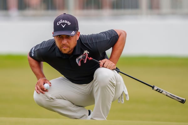 FILE - Xander Schauffele checks his line before putting on the 18th green during the third round of the Tour Championship golf tournament, Saturday, Aug. 31, 2024, in Atlanta. (AP Photo/Jason Allen, File)