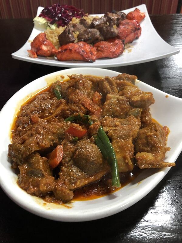 The Shinwari goat karahi at Ariana Kabob House in Duluth is a goat stew in a rich currylike gravy. A plate of tandoori chicken and tikka lamb appears in back. CONTRIBUTED BY WENDELL BROCK