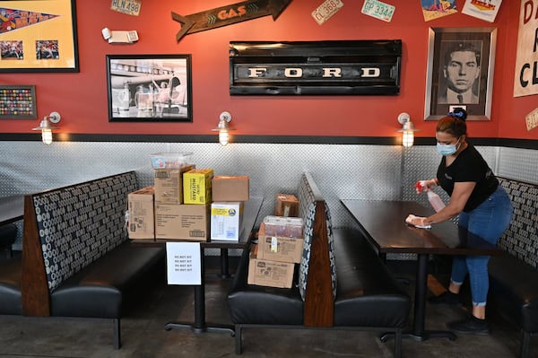 April 25, 2020 Decatur - Leah Johnson, employee, uses a disinfectant wipe to sanitize tables as restaurant staff prepare to reopen the restaurant at Bad Daddy's Burger Bar in Decatur on Saturday, April 25, 2020. On Monday, Kemp announced shuttered businesses including barbershops, beauty and nail salons, spas, gyms and bowling alleys could reopen Friday. Movie theaters and restaurant dining rooms can reopen Monday. (Hyosub Shin / Hyosub.Shin@ajc.com)