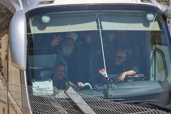 A member of the Syrian Druze community waves as he is welcomed by Druze clerics at the border with Syria, as he enters into the village of Majdal Shams, in the Israeli-controlled Golan Heights, Friday, March 14, 2025. (AP Photo/Leo Correa)