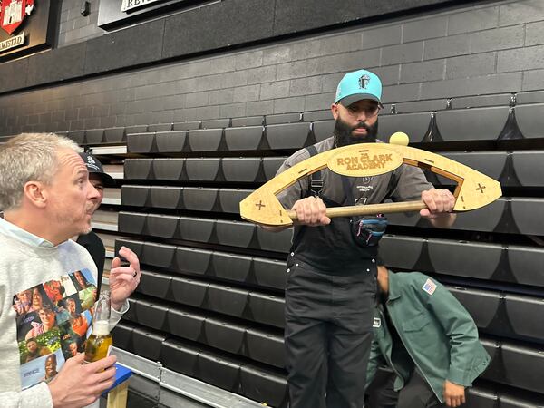 Omar Lopez tries out one of the challenges inspired by "Survivor" at a viewing party at Ron Clark Academy with Clark himself (left) on April 12, 2023. RODNEY HO/rho@ajc.com