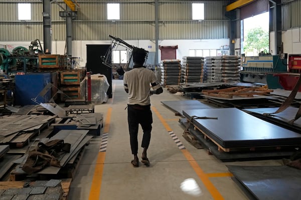 A worker carries steel waste at a factory in a suburb of Bengaluru, India, Thursday, Feb. 27, 2025. (AP Photo/Aijaz Rahi)