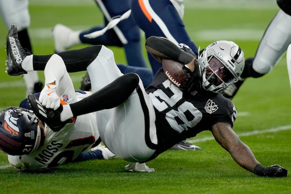 Denver Broncos cornerback Riley Moss tackles Las Vegas Raiders running back Sincere McCormick (28) during the first half of an NFL football game, Sunday, Nov. 24, 2024, in Las Vegas. (AP Photo/John Locher)