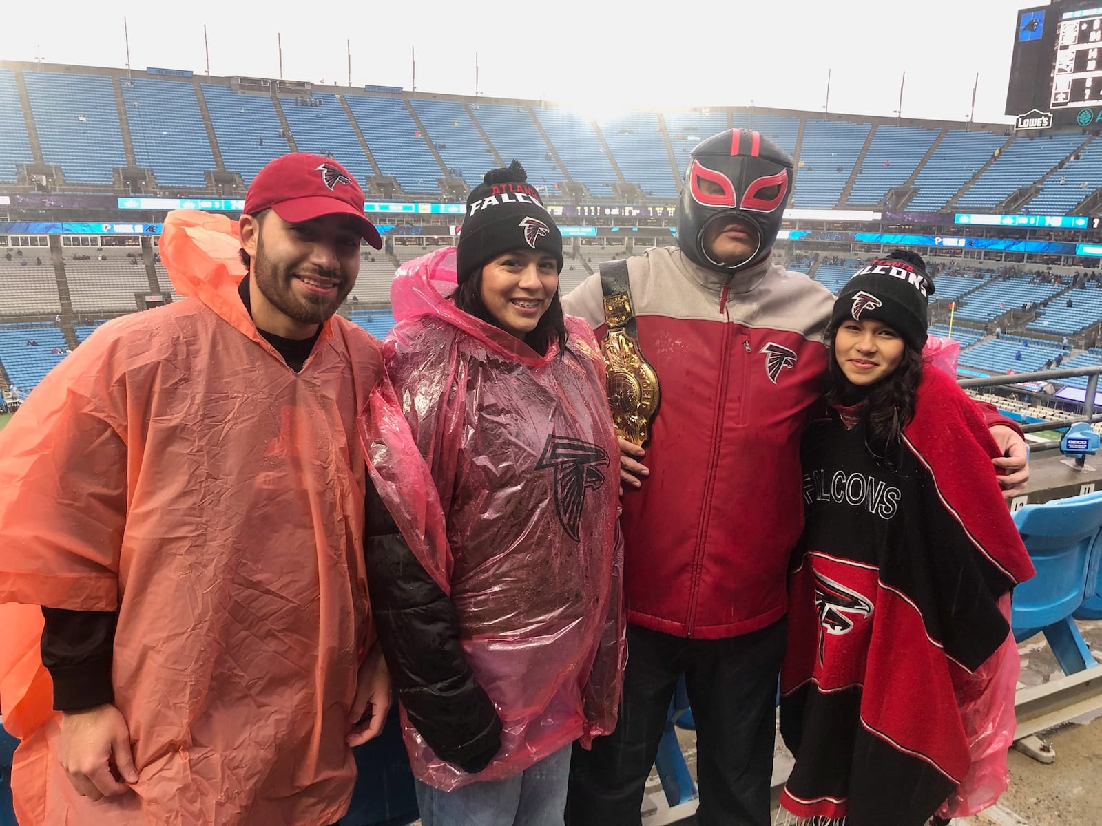 Falcons fans (from left) Arturo Cuenca, Fabiola Alvarado, Carlos Silva and Kayla Silva pose for a photo during halftime of the Falcons-Panthers game at Bank of America Stadium in Charlotte, North Carolina Dec. 17, 2023. (AJC photo by Ken Sugiura)