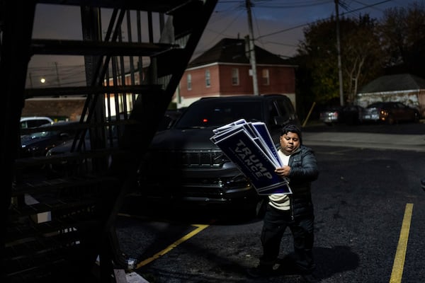 Arif Armanjisan helps carry yard signs into a campaign office for Republican presidential nominee former President Donald Trump the night before the general election Monday, Nov. 4, 2024, in Hamtramck, Mich. (AP Photo/David Goldman)