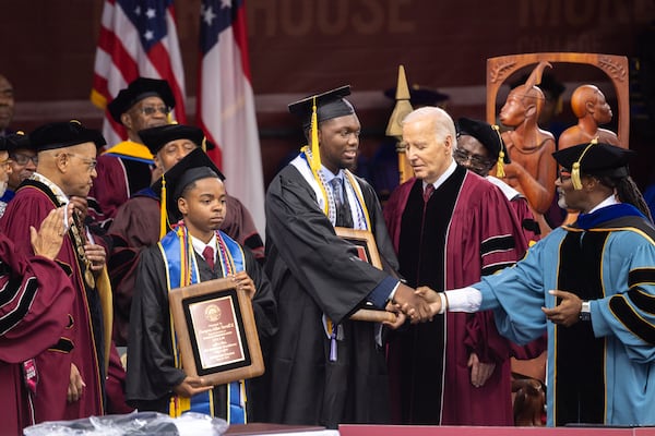 Morehouse valedictorian DeAngelo Jeremiah Fletcher (center) is seen as President Joe Biden (right) and Morehouse President David A. Thomas (far left), look on at the commencement ceremony at Morehouse College in Atlanta on Sunday, May 19, 2024. (Arvin Temkar / AJC)