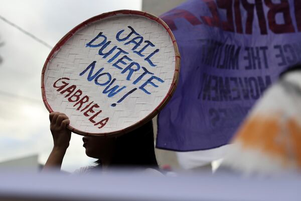 A person holds a sign against former Philippine President Rodrigo Duterte following his arrest in Quezon City, Philippines, Tuesday, March 11, 2025. (AP Photo/Basilio Sepe)