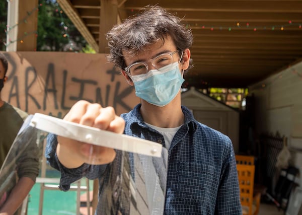 Edward Aguilar shows off a face shield that he and his friends created, along with other PPE, at a residence in Alpharetta.. ALYSSA POINTER / ALYSSA.POINTER@AJC.COM