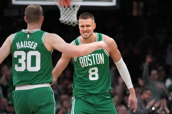 Boston Celtics center Kristaps Porzingis (8) celebrates with forward Sam Hauser (30) during the first half of an NBA basketball game against the Detroit Pistons, Wednesday, Dec. 4, 2024, in Boston. (AP Photo/Charles Krupa)