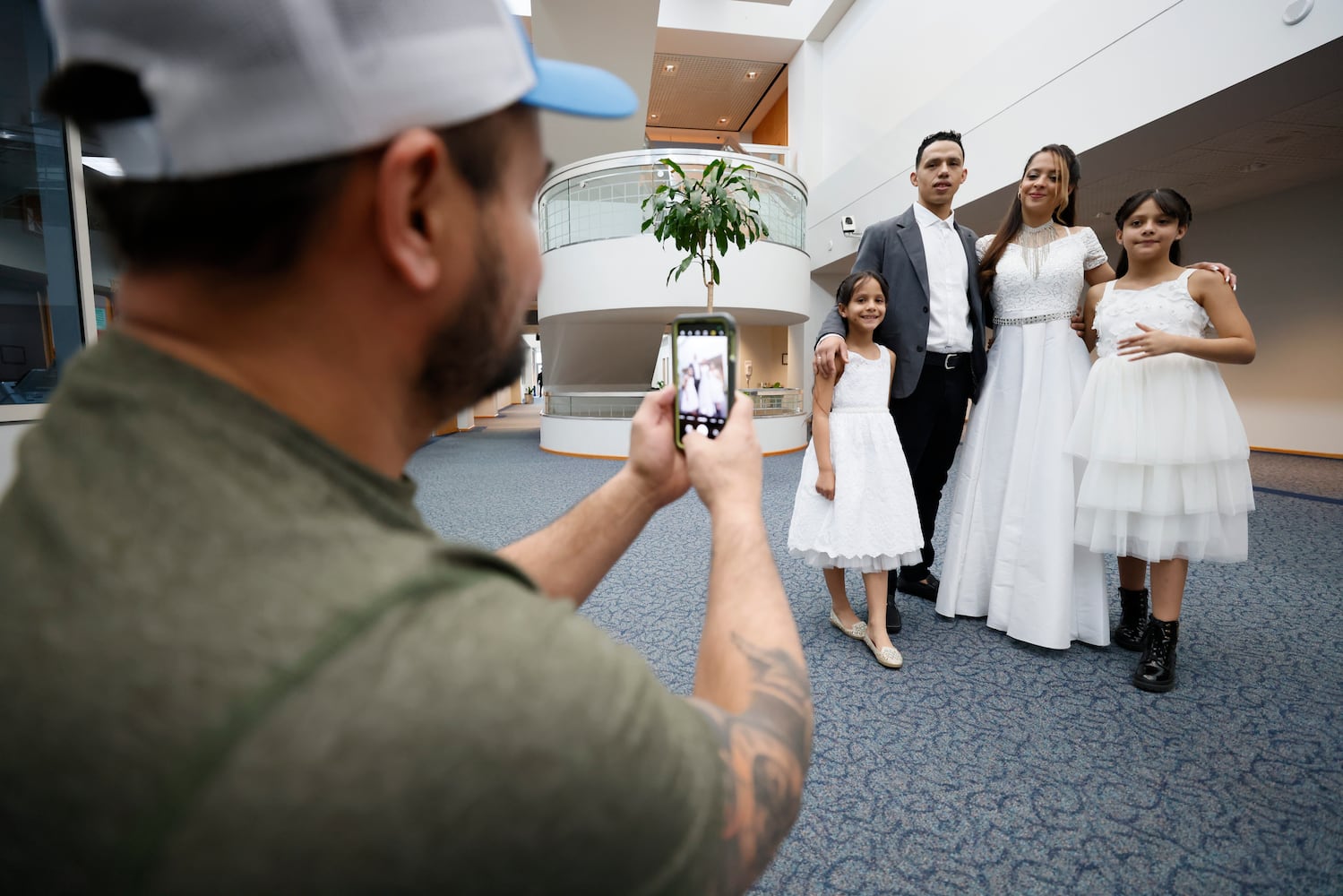 Alex Rivera takes a photo of Gonzalo Orrego with María Pérez and their daughters Luciana and Isabella Orrego after they married at the Gwinnett County Courthouse in Lawrenceville on Valentine’s Day, Tuesday, February 14, 2023. Miguel Martinez / miguel.martinezjimenez@ajc.com