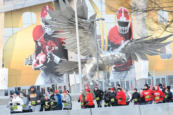 Participants run past Mercedes-Benz Stadium as they compete in the Extra Yard 5K, the official race of the College Football Playoff National Championship, on Sunday Jan. 7, 2018, in Atlanta. About 2,000 runners competed. More than 100,000 visitors are expected for Monday night’s game and related events over the weekend. 