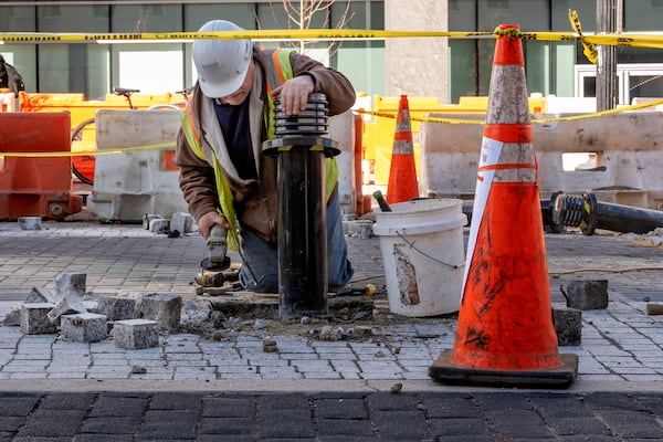 A worker leans on a traffic bollard during demolition of the Black Lives Matter mural, Monday, March 10, 2025, in Washington. (AP Photo/Jacquelyn Martin)