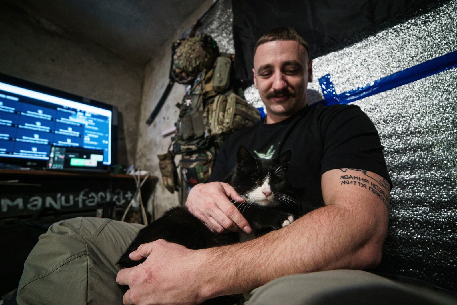 Illya Zelinskiy, Ukrainian commander of a unit Bugskiy Gard pets a cat on the front line, in Kherson region, Ukraine, Saturday, Nov. 2, 2024. (AP Photo/Marko Ivkov)