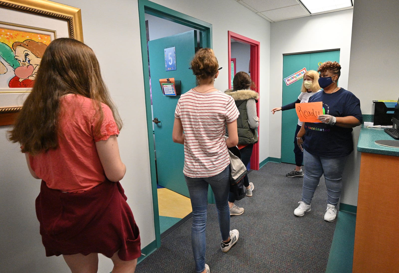 Medical assistant Melissa Dalton, right, and Dr. Debby Pollack, second from right, greet patients at DeKalb Pediatric Center last week. There was a surge in demand from families in DeKalb County after the Pfizer-BioNTech vaccine as authorized for ages 12-15. Other parts of the state saw far less demand. (Hyosub Shin / Hyosub.Shin@ajc.com)