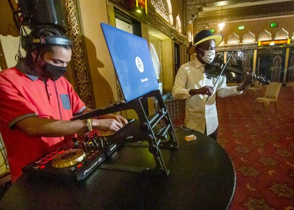 Ashanti Floyd, right, plays music while people wait after getting their COVID vaccination in the lobby of the Fox Theatre earlier this week. (Steve Schaefer for The Atlanta Journal-Constitution)