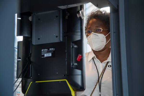 A system specialist for the Fulton County department of registration and elections [name withheld] inspects each voting machine on the floor at State Farm Arena in Atlanta, Wednesday, October 7, 2020. (Alyssa Pointer / Alyssa.Pointer@ajc.com)