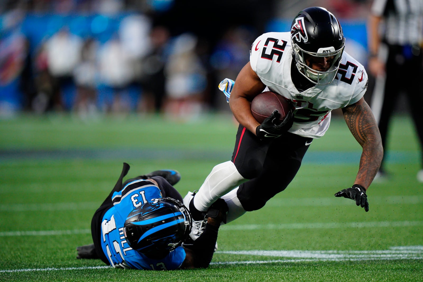 Carolina Panthers cornerback Troy Hill (13) tackles Atlanta Falcons running back Tyler Allgeier (25) in the second half of an NFL football game in Charlotte, N.C., Sunday, Oct. 13, 2024. (AP Photo/Jacob Kupferman)