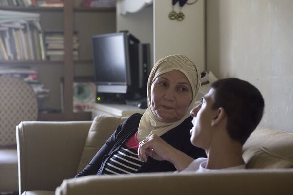 Alan Youssef visits with family friend Saadia Mohamed Kelli in his Decatur home. Chad Rhym / Chad.Rhym@ajc.com