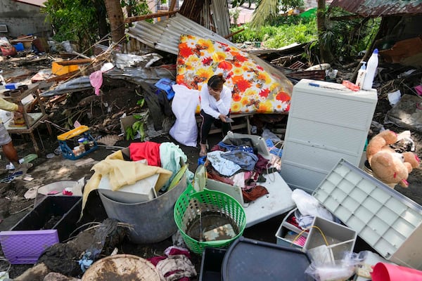 A resident sits beside belongings from their damaged home after a recent landslide triggered by Tropical Storm Trami struck Talisay, Batangas province, Philippines leaving thousands homeless and several villagers dead on Saturday, Oct. 26, 2024. (AP Photo/Aaron Favila)