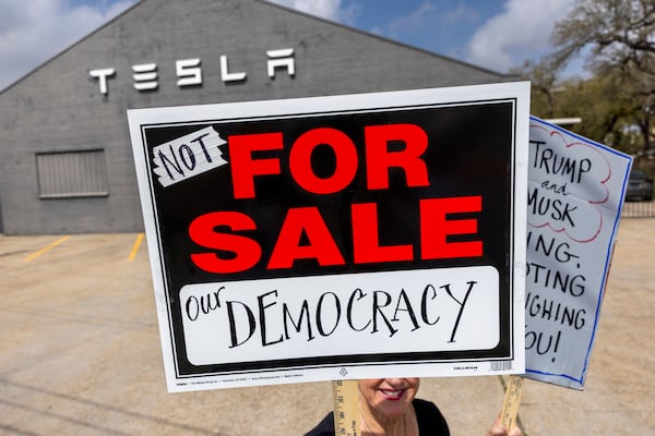 Protesters outside a Tesla Service Center on Tchoupitoulas Street in New Orleans express their issues with Elon Musk and President Donald Trump on Friday, March 14, 2025. (Chris Granger/The Times-Picayune/The New Orleans Advocate via AP)