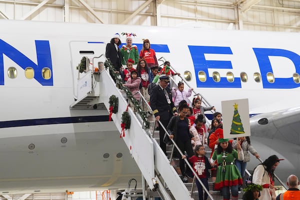 Participants deplane during the United Airlines annual "fantasy flight" to a fictional North Pole at Denver International Airport, Saturday, Dec. 14, 2024, in Denver. (AP Photo/David Zalubowski)