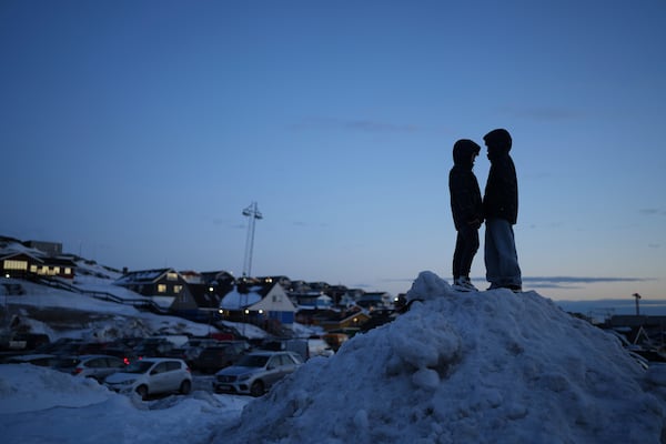 Locals stand on a pile of snow during parliamentary elections, in Nuuk, Greenland, Tuesday, March 11, 2025. (AP Photo/Evgeniy Maloletka)