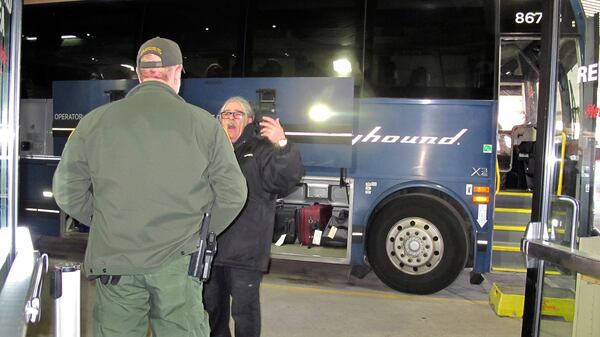 A  worker speaks with a Customs and Border Protection agent seeking to board a Greyhound bus.