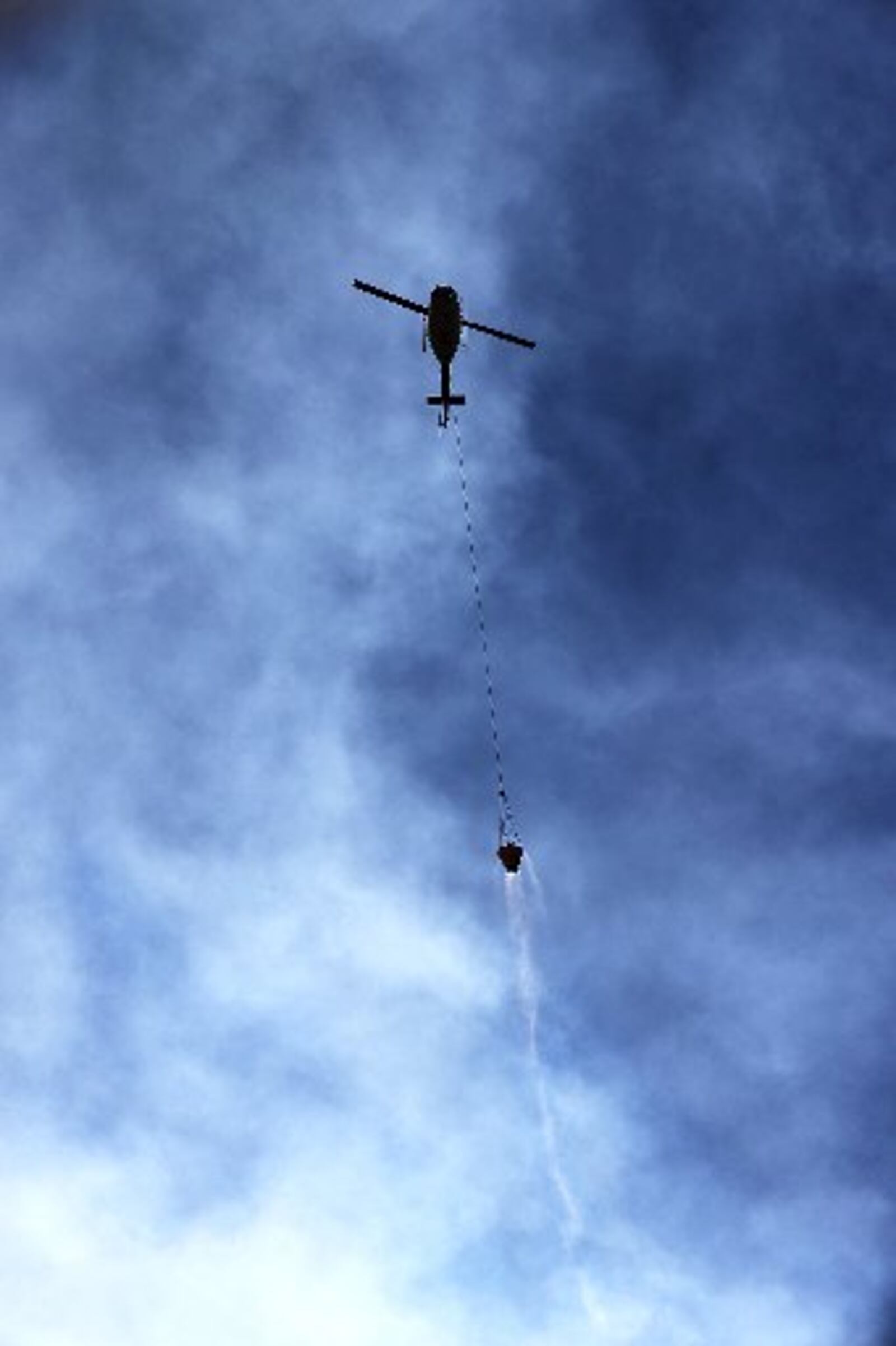 A helicopter is surrounded by smoke while flying a bucket of water to fight the Rock Mountain fire Monday. CURTIS COMPTON / CCOMPTON@AJC.COM