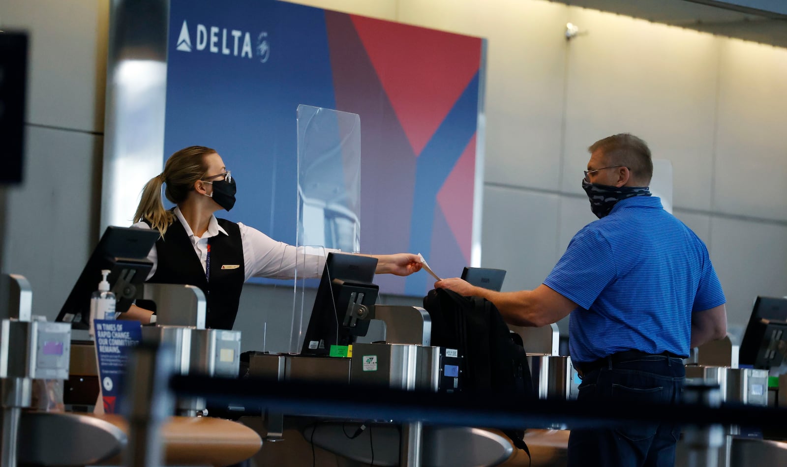 In this file photo, a ticketing agent for Delta Airlines hands a boarding pass to a passenger as he checks in for a flight in the main terminal of Denver International Airport in Denver .(AP Photo/David Zalubowski)