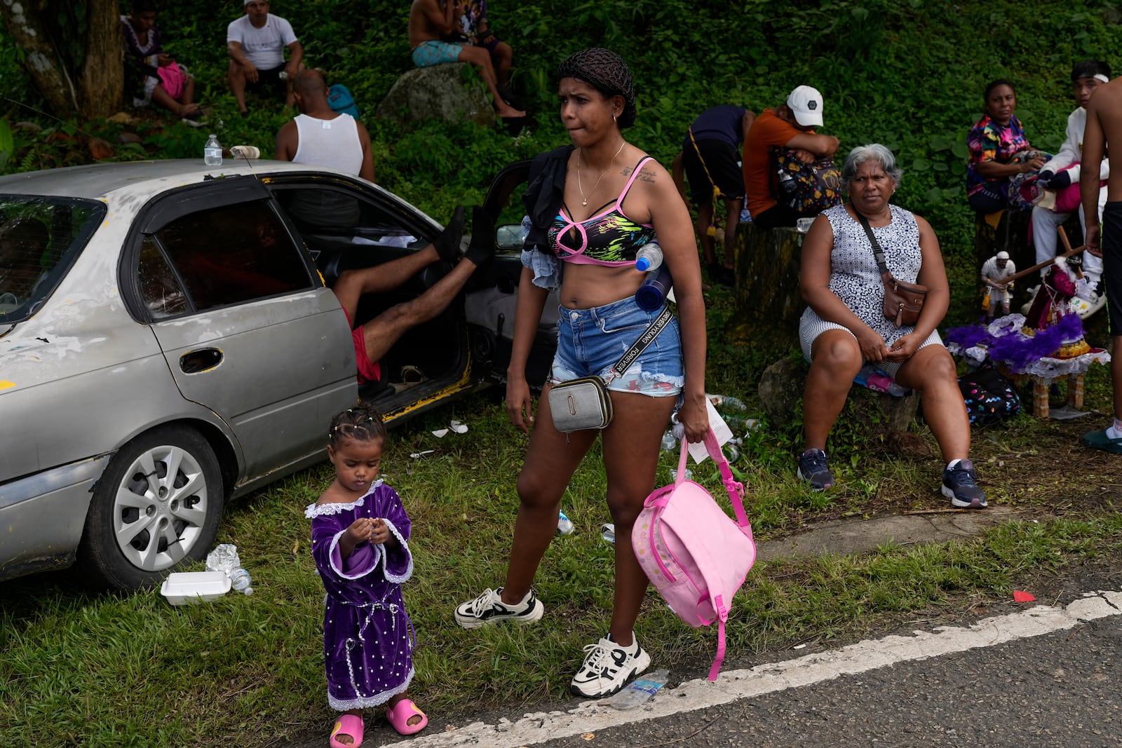 Pilgrims rest on the side of the road after leaving San Felipe Church to honor the Black Christ in Portobelo, Panama, Monday, Oct. 21, 2024, during a festival celebrating the iconic statue that was found on the shore in 1658. (AP Photo/Matias Delacroix)