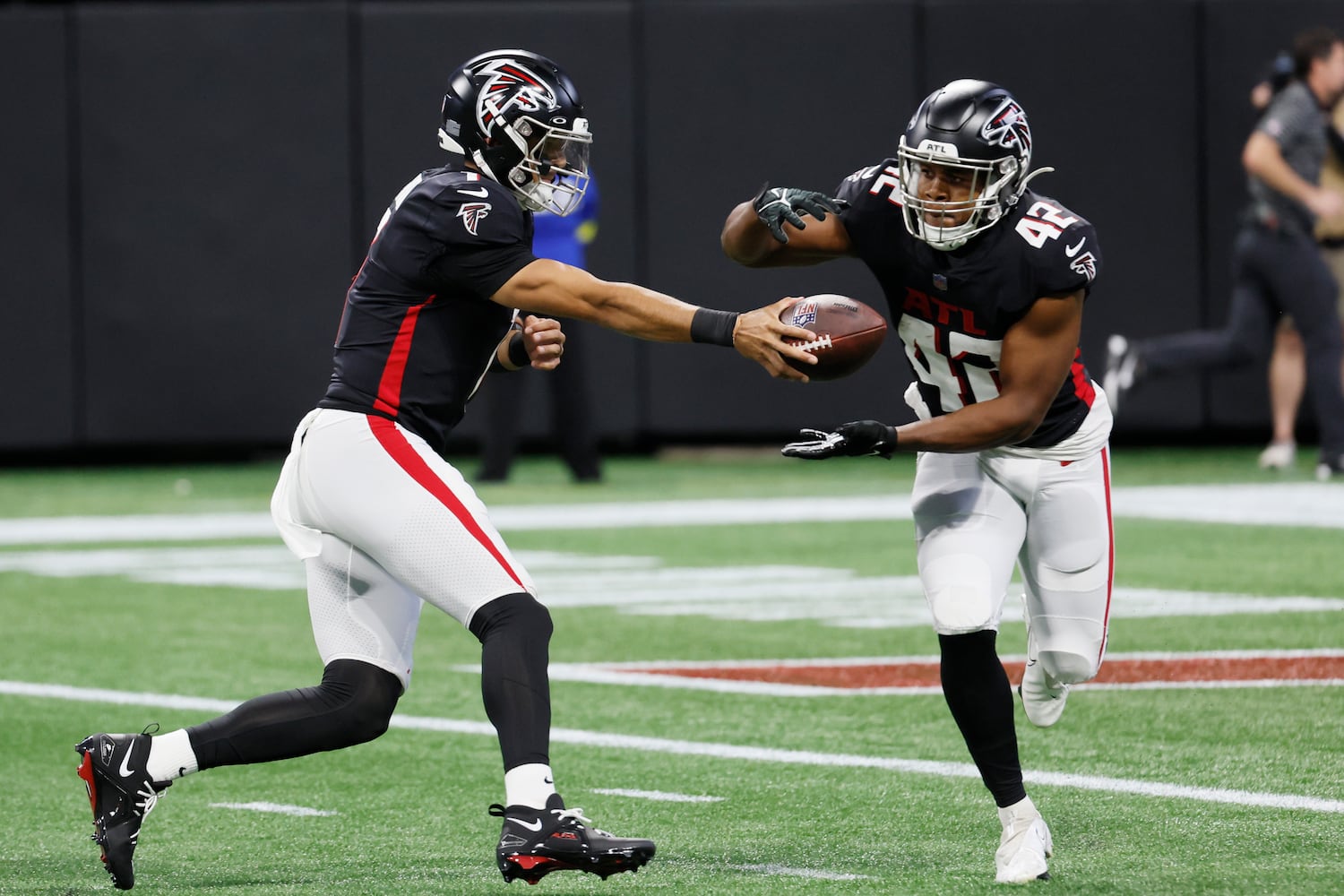 Falcons quarterback Marcus Mariota hands the ball to running back Caleb Huntley during the second quarter Sunday at Mercedes-Benz Stadium. (Miguel Martinez / miguel.martinezjimenez@ajc.com)
 