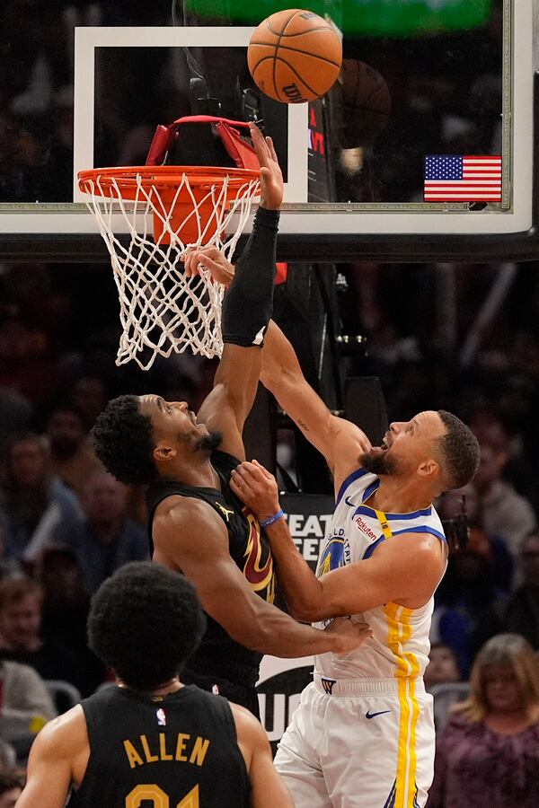 Golden State Warriors guard Stephen Curry, right, shoots as Cleveland Cavaliers guard Donovan Mitchell, left, defends in the second half of an NBA basketball game, Friday, Nov. 8, 2024, in Cleveland. (AP Photo/Sue Ogrocki)