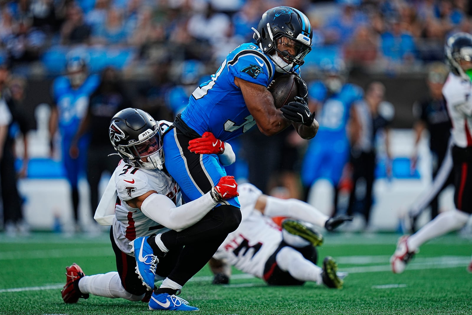 Carolina Panthers running back Chuba Hubbard (30) runs the ball against Atlanta Falcons safety Justin Simmons (31) in the first half of an NFL football game in Charlotte, N.C., Sunday, Oct. 13, 2024. (AP Photo/Rusty Jones)