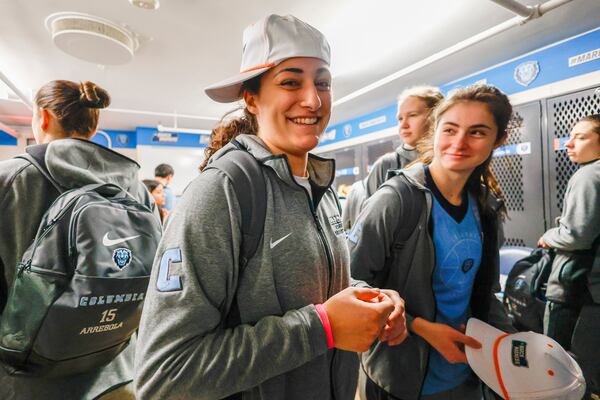 Columbia guard Emily Montes tries on her hat from her swag bag as the Columbia basketball team arrives at Carmichael Arena on the campus of the University of North Carolina in Chapel Hill, N.C., Wednesday, March 19, 2025, before their First Four basketball game in the NCAA Tournament against Washington on March 20. (AP Photo/Nell Redmond)