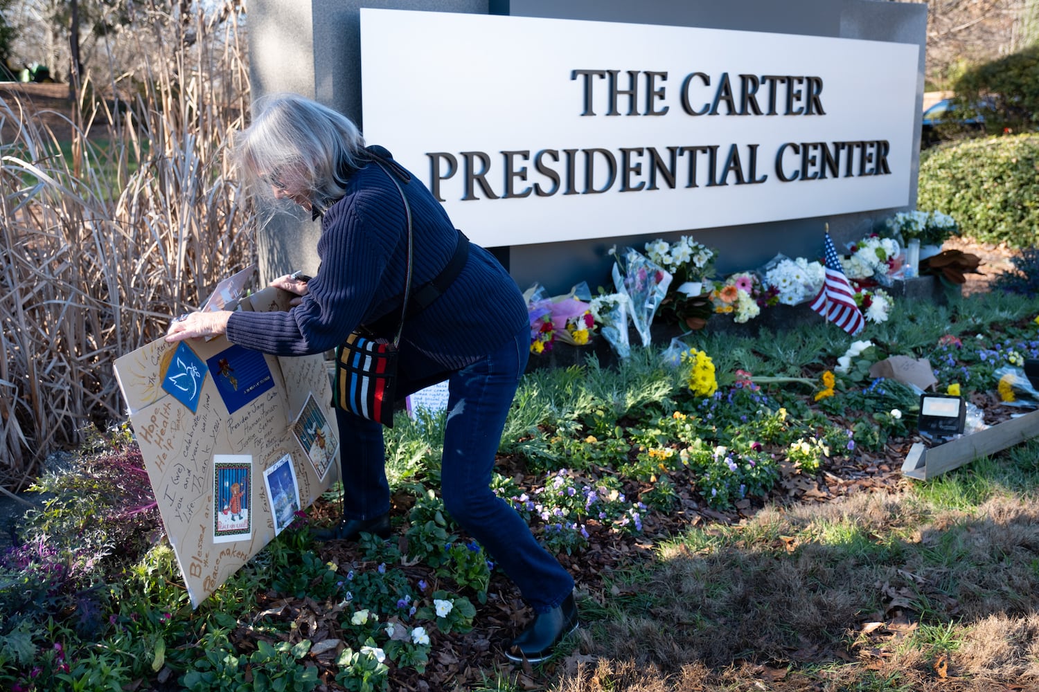 Jennifer Lund brings a handmade sign to the makeshift memorial to former President Jimmy Carter at the Carter Center in Atlanta on Monday, Dec. 30, 2024. Lund said she thinks Carter was one of the most incredible human beings.   Ben Gray for the Atlanta Journal-Constitution