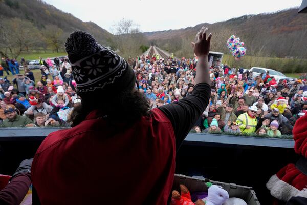 A volunteer tosses toys to people during the 82nd run of the CSX Santa Train, Saturday, Nov. 23, 2024, in Kermit, Va. (AP Photo/George Walker IV)