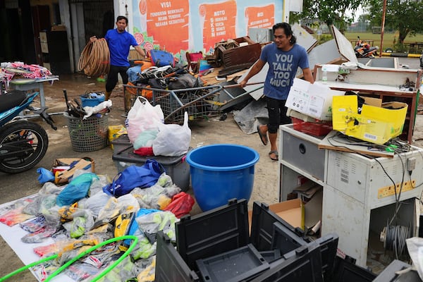 Men remove items from a school affected by a flood in Tumpat, on the outskirts of Kota Bahru, Malaysia, Tuesday, Dec. 3, 2024. (AP Photo/Vincent Thian)