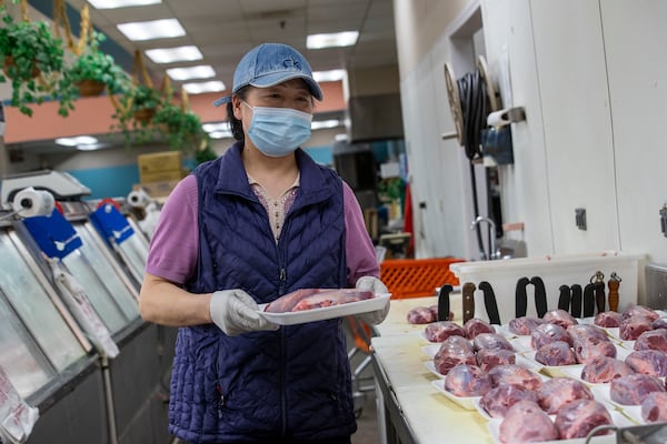 Yan Ning, an employee at the Dinho Supermarket of Atlanta, wears a mask and gloves while wrapping pairs of beef shanks to sell in the meat department at the grocery store located inside the Atlanta Chinatown Shopping Mall in Chamblee, Friday, July 31, 2020. (ALYSSA POINTER / ALYSSA.POINTER@AJC.COM)