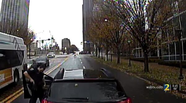 An Atlanta police officer appears to holster his weapon during a road rage altercation with a MARTA bus driver.